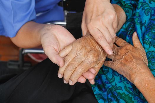 elderly woman holding hand with caregiver