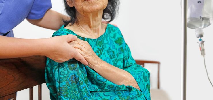 elderly woman holding hand with caregiver