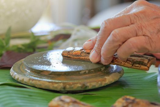 Thanaka herb bark scrubbing on kyauk pyin stone slab . thanaka is a popular cosmetic paste made from ground bark in Myanmar