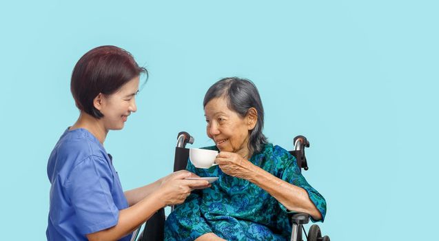 elderly woman gets a teacup from caregiver