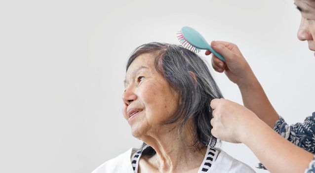 elderly woman combing hair by caregiver