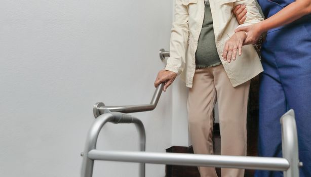 Elderly woman holding on handrail with caregiver