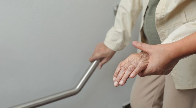 Elderly woman holding on handrail with caregiver