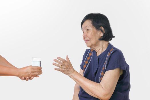 elderly woman gets a glass of water from caregiver