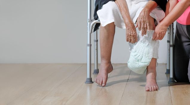 elderly woman changing diaper with caregiver