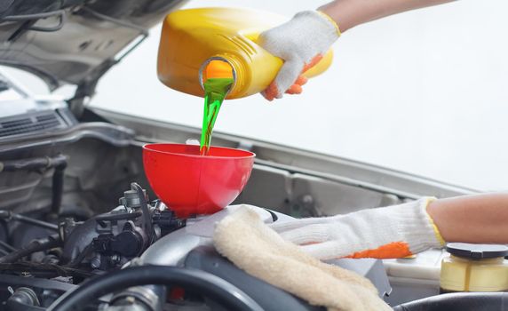 Car mechanic pouring new oil to engine.