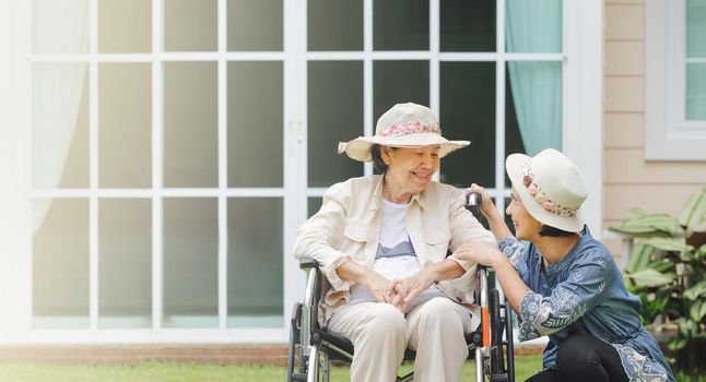 Elderly woman relax on wheelchair in backyard with daughter