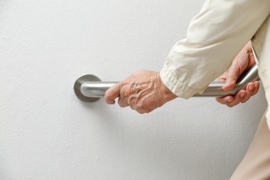 Elderly woman holding on handrail for safety walk steps