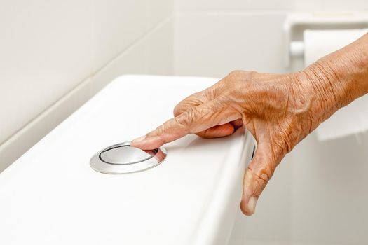 Elderly woman hand flushing toilet