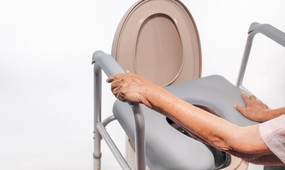 Elderly woman using mobile toilet seat chair