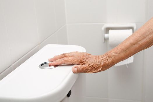 Elderly woman hand flushing toilet