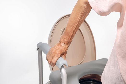 Elderly woman using mobile toilet seat chair