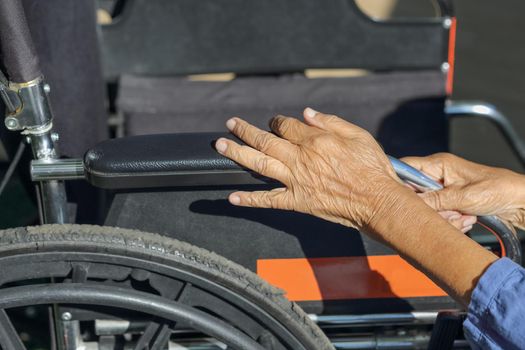 Elderly hands on a wheelchair.