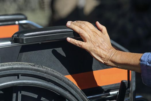 Elderly hands on a wheelchair.