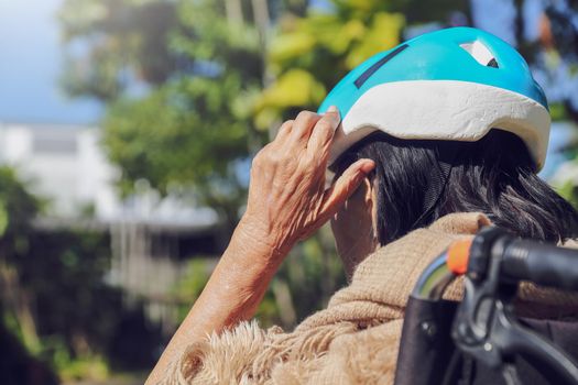 elderly woman in backyard puts on a safety head protection helmet from​ the  risk of falling