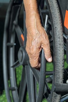 Elderly hands on a wheelchair.