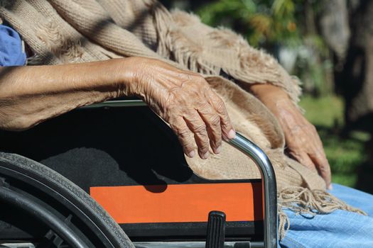 Elderly hands on a wheelchair.