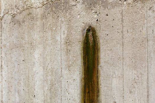 Weeping hole with slurry stain on a concrete retention wall. Close-up with selective focus.