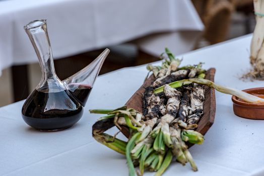 Roasted Calcots onions served on plate with Romesco sauce – traditional Catalan winter dish.