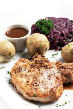 german style grilled pork chop with bread dumplings and red cabbage traditional meal on white background