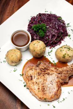 german style grilled pork chop with bread dumplings and red cabbage traditional meal on wood table