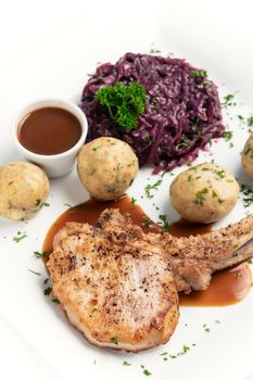 german style grilled pork chop with bread dumplings and red cabbage traditional meal on white background