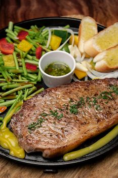 organic tenderloin beef steak sizzler on hot plate meal platter with mixed vegetables and chimichurri sauce