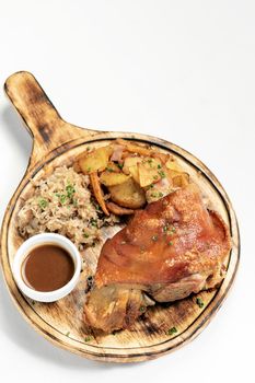 SCHWEINSHAXE traditional german pork knuckle with sauerkraut and potatoes meal on white background