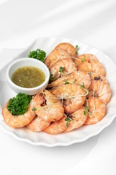 fresh boiled prawns with zesty citrus dipping sauce on white background