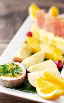 mixed fresh cut organic fruit salad platter outdoors on wood table