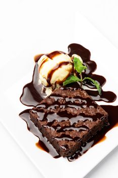vegan chocolate brownie dessert with dairy-free coconut milk vanilla ice cream with caramel sauce on white background in studio