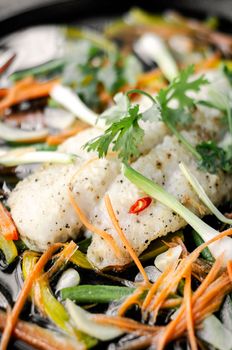 chinese cantonese style steamed spicy fish fillet with vegetables on hot plate