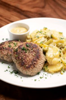 german frikadellen meatballs with creamy onion fried potatoes and mustard sauce on wood table background