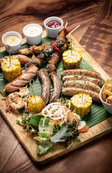 organic mixed grill barbecue meat platter rustic set meal with sausages, skewers, side dishes and sauces