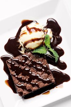 vegan chocolate brownie dessert with dairy-free coconut milk vanilla ice cream with caramel sauce on white background in studio