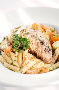 fried chicken breast with penne and saute vegetables pasta dish on white background