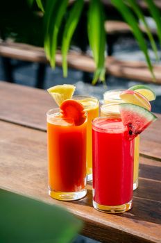 mixed fresh organic fruit juice glasses selection on sunny garden table