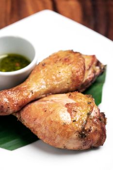 roast chicken drumsticks appetizer with spicy thai green chilli sauce on white plate