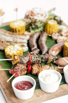 organic mixed grill barbecue meat platter rustic set meal with sausages, skewers, side dishes and sauces on white background