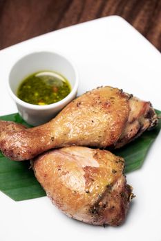roast chicken drumsticks appetizer with spicy thai green chilli sauce on white plate