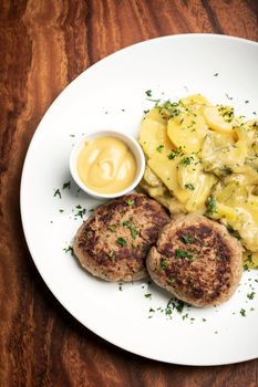 german frikadellen meatballs with creamy onion fried potatoes and mustard sauce on wood table background