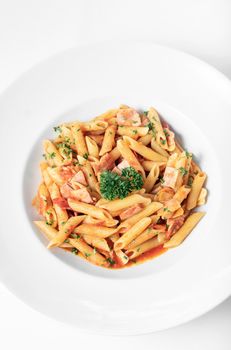 penne amatriciana organic tomato and ham sauce pasta dish on white table