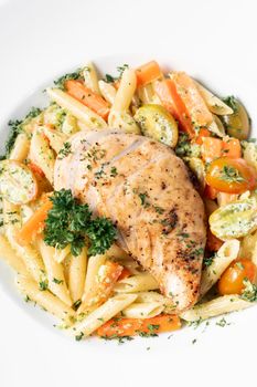 fried chicken breast with penne and saute vegetables pasta dish on white background