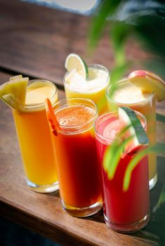 mixed fresh organic fruit juice glasses selection on sunny garden table