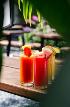 mixed fresh organic fruit juice glasses selection on sunny garden table