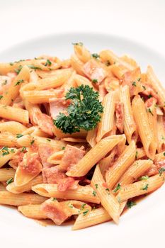 penne amatriciana organic tomato and ham sauce pasta dish on white table