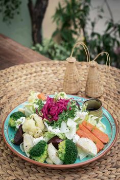 rustic cottage salad with healthy mixed steamed and fresh vegetables on colorful plate outdoors in garden