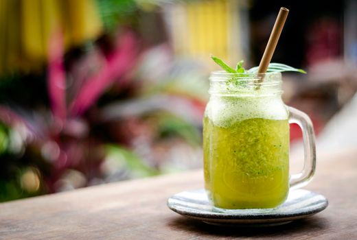 organic pineapple kiwi and basil fruit detox healthy smoothie drink outdoors in glass