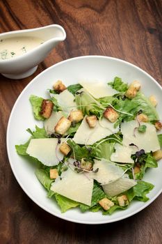 caesar salad with parmesan cheese and croutons on wood table