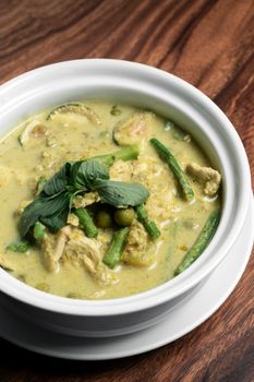 thai green curry with chicken and vegetables on wood table